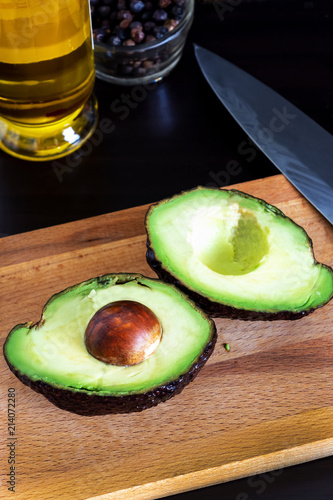 Cut ripe avocado Haas on cutting board. Dark wooden background. Selective focus. Closeup.