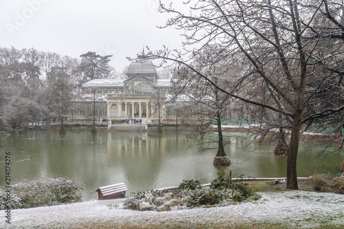 view of the glass palace under a big snowfall in the Retiro Park of Madrid, Spain.