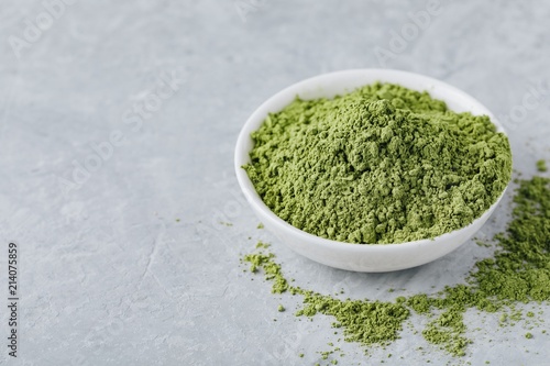 Green matcha tea powder in white bowl