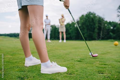 cropped shot of woman playing golf while friends standing near by at golf course