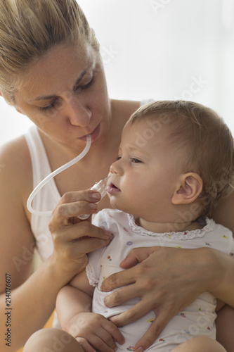 mother cleaning babies nose. nasal aspiration cleaner