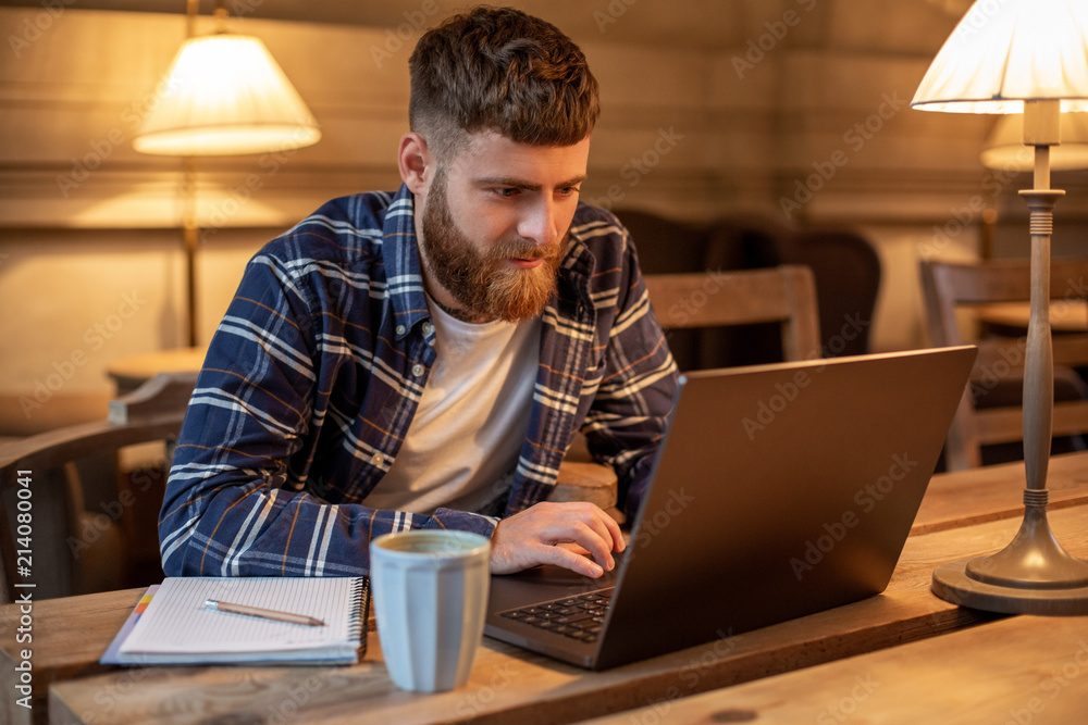 Young professional surfing the Internet on his laptop in a cafe Young professional surfing the Internet on his laptop in a cafe