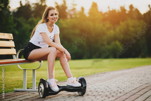 Young attractive woman with hoverboard outdoors in the park at the sunset. Toned photo