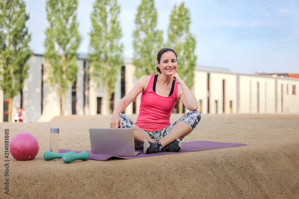 fit woman watching online fitness program and doing workout infront of a laptop on a mat