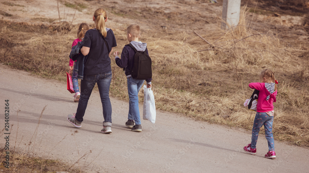 Mother with three children walking along the road Mother with three children walking along the road