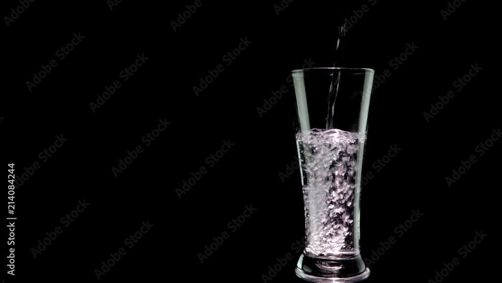Water pouring into glass on black background Water pouring into glass on black background