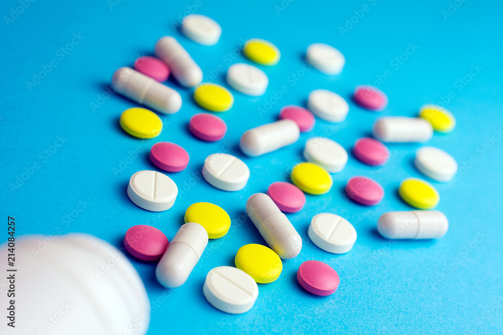 Pills tablets capsule plastic drugs bottle blue background. Drug prescription for treatment concept.