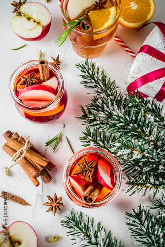 Traditional winter drinks, white and red mulled wine cocktail, with white and red wine, spices, apple, orange. On white marble background copy space