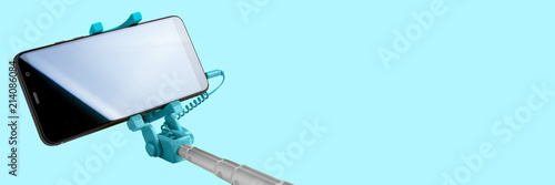 Monopod for selfie with smart phone. Selfie stick with smartphone isolated on blue background, banner photo