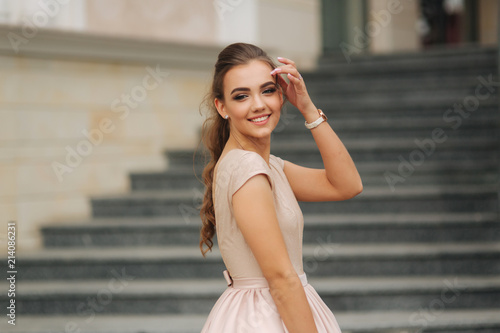 Elegant brunette lady stand on stairs by the hotel