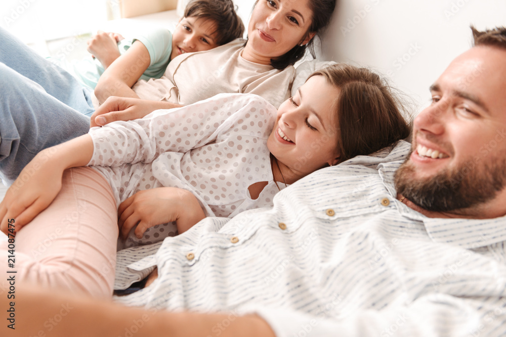 Portrait of caucasian family with siblings 8-10 laughing, and lying together on bed indoor Portrait of caucasian family with siblings 8-10 laughing, and lying together on bed indoor