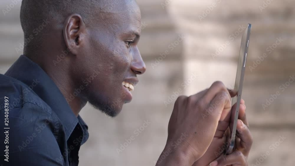 Smiling young african man using digital tablet. Technology,fun,youth- profile Smiling young african man using digital tablet. Technology,fun,youth- profile
