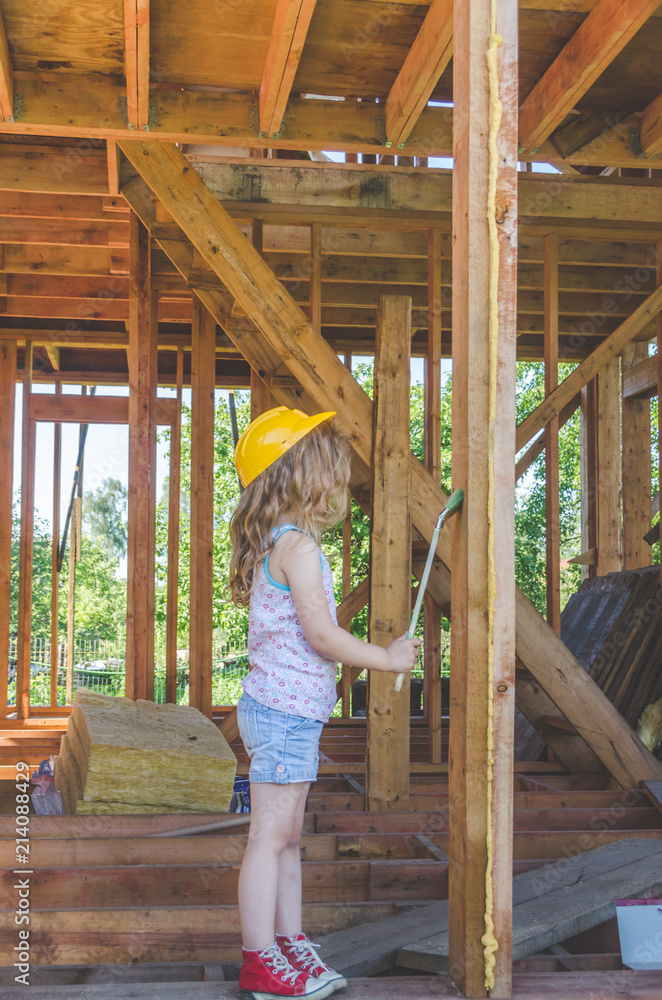 child paints the frame of a wooden house child paints the frame of a wooden house