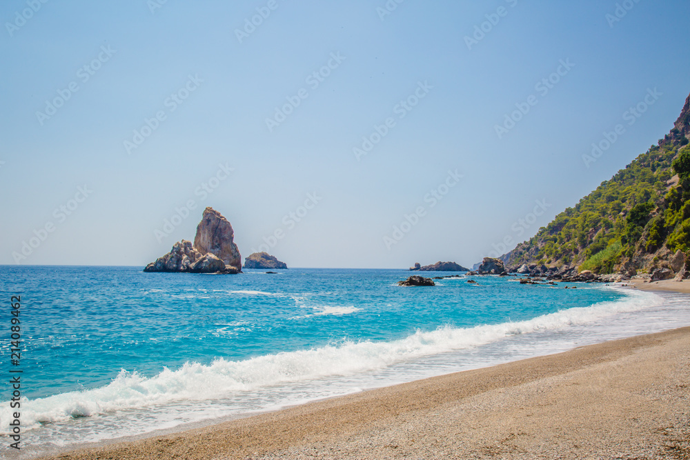 Sand, wild beach coast with sea or ocean and mountain rocks 