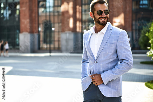 Slika na platnu Portrait of sexy handsome fashion businessman model dressed in elegant blue suit posing on street background