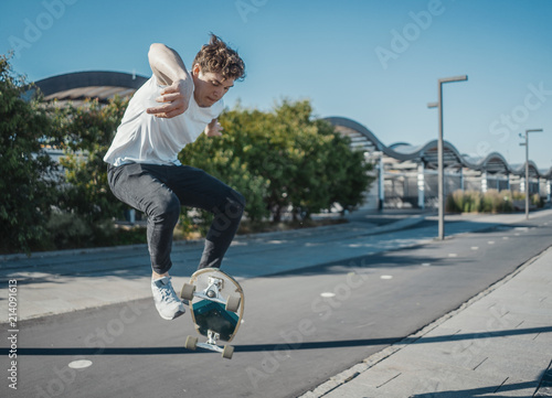 Young attractive man riding longboard in the park.