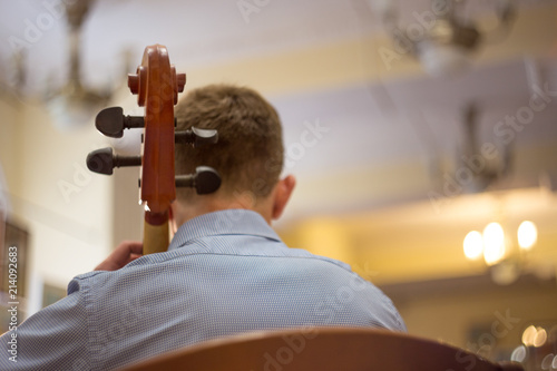 close up of a man playing the cello, a real concert, rear view