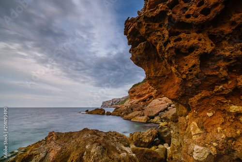 Sunset on the beach among the rocks near the city of Denia. District of Valencia, Spain. photo