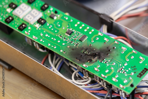 Close up burnt green microchip after short circuit due to water damage. Damaged overheat control panel board of cooking stove