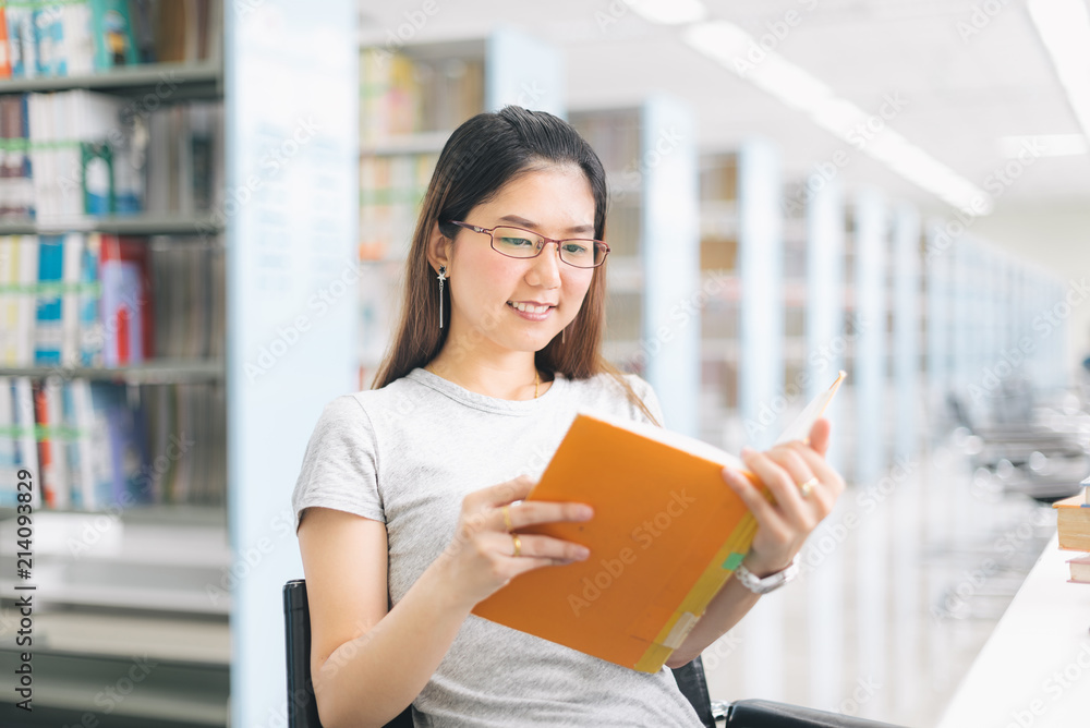Asian Woman reading and sitting on the chair in the library.. Asian Woman reading and sitting on the chair in the library..