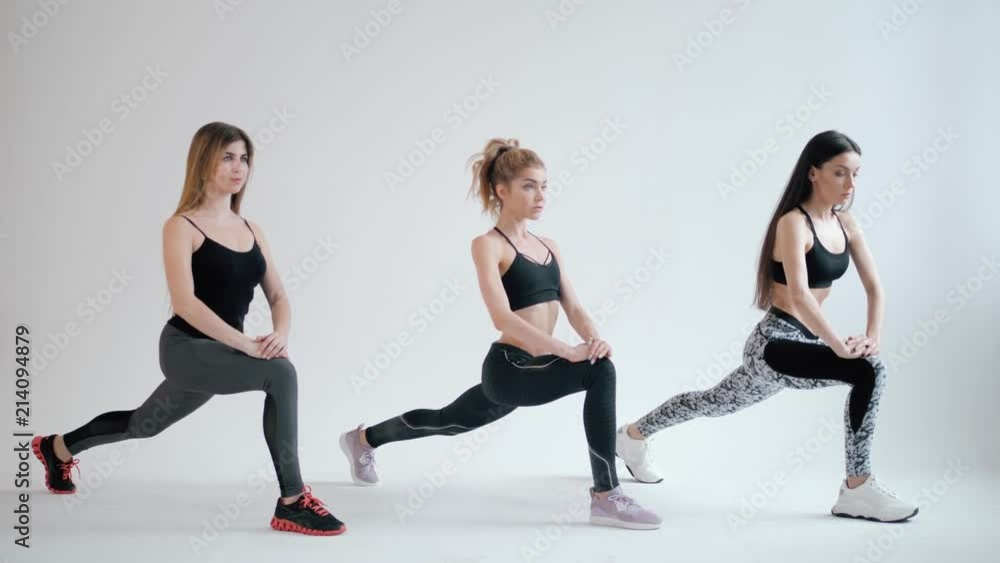 Group of young sporty attractive people girls womans practicing yoga lesson with instructor, standing together in exercise, working out, indoor full length, studio background fat burn Group of young sporty attractive people girls womans practicing yoga lesson with instructor, standing together in exercise, working out, indoor full length, studio background fat burn
