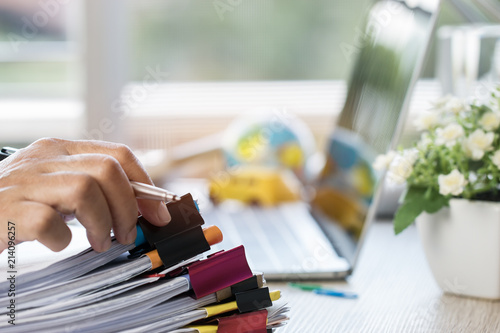 Tableau sur toile Businessman hands holding pen for working in Stacks of paper files searching inf