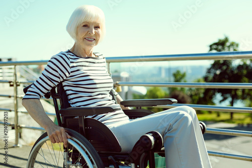 Strong mind. Beautiful senior woman keeping smile on her face and sitting in semi position while looking straight at camera