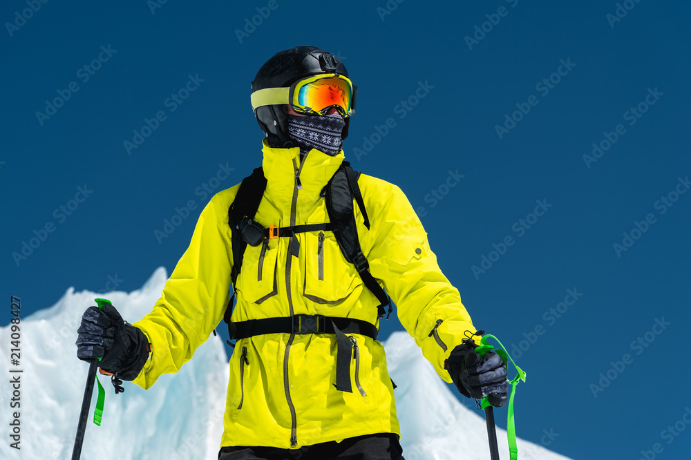 Skier standing on a slope. Man in a light suit, the helmet and mask in skiing is to ski. In the background snow-capped mountains , skiers . Caucasus Mountains, Elbrus, Russia Skier standing on a slope. Man in a light suit, the helmet and mask in skiing is to ski. In the background snow-capped mountains , skiers . Caucasus Mountains, Elbrus, Russia