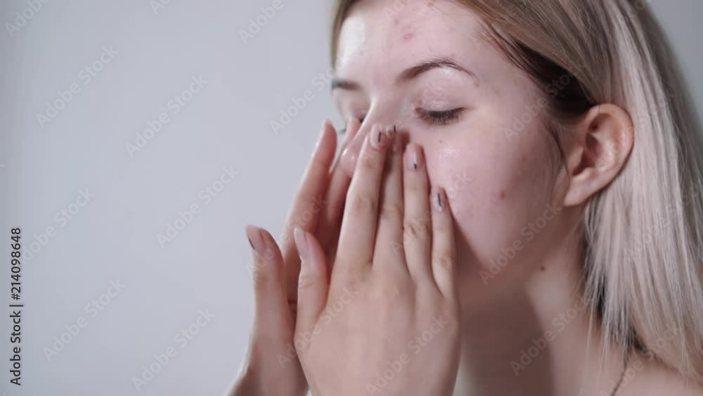 Beauty smiling teen girl cleaning her face with cotton pad and cleansing lotion. Young happy woman enjoying her skin, smiling in the mirror, skin care concept Beauty smiling teen girl cleaning her face with cotton pad and cleansing lotion. Young happy woman enjoying her skin, smiling in the mirror, skin care concept