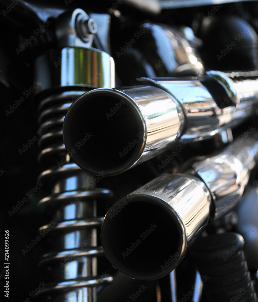 close up rear view of a powerful classic black vintage motorcycle showing suspension and shiny chrome exhaust pipes close up rear view of a powerful classic black vintage motorcycle showing suspension and shiny chrome exhaust pipes