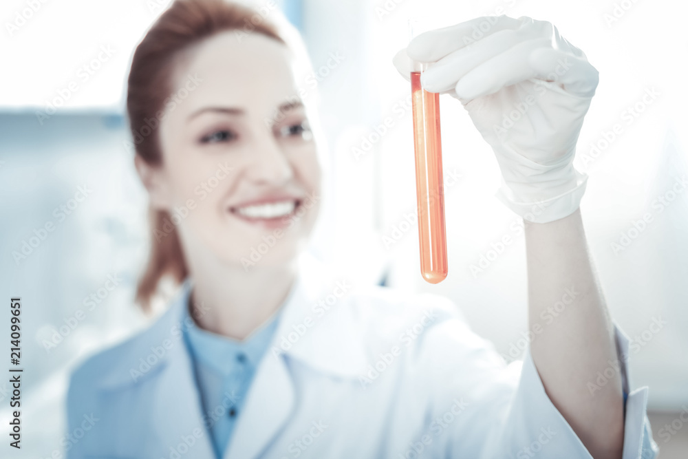 Biological sample. Selective focus of test liquid being held be a professional delighted scientist while working in the lab Biological sample. Selective focus of test liquid being held be a professional delighted scientist while working in the lab