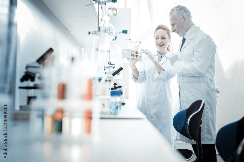 Obraz premium Cooperation of colleagues. Positive smart professional scientists standing together and discussing work while working together on a project