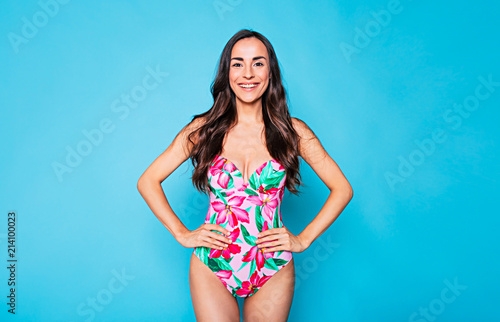Funny beautiful and young smiling woman with long curly hair in colorful swim wear, cute girl posing on blue background. Rest by the sea, Summer relax and Vacation © My Ocean studio