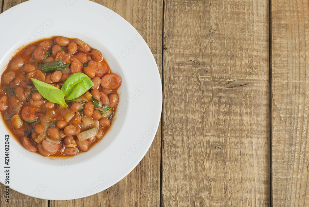 Cooked Red Beans in Tomato Sauce with Spinach and Onion, white Round Plate, Wooden Background, Top view, Copy space. Cooked Red Beans in Tomato Sauce with Spinach and Onion, white Round Plate, Wooden Background, Top view, Copy space.