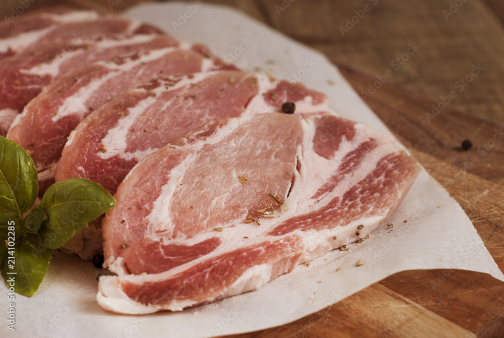 Raw pork meat with spices, wooden cutting board. Food Cooking Ingredient. Top view with copyspace. Raw pork meat with spices, wooden cutting board. Food Cooking Ingredient. Top view with copyspace.