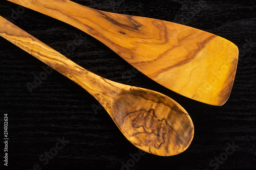 Group of two whole kitchen tool olive wood spoon and flat spatula flatlay on black wood