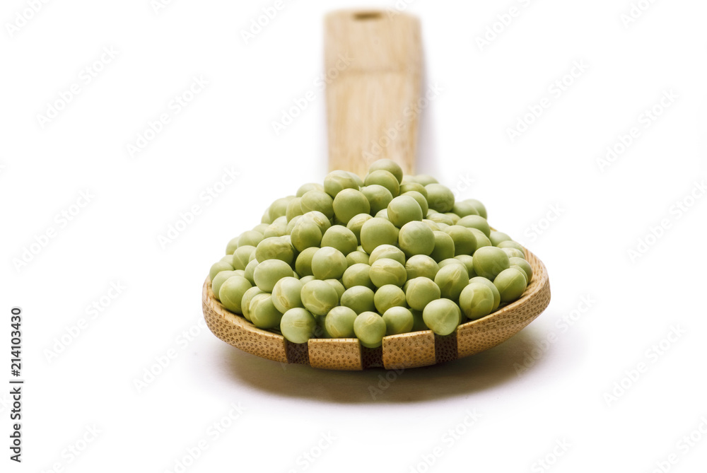 Green peas in wooden scoop spoon isolated on white background Green peas in wooden scoop spoon isolated on white background