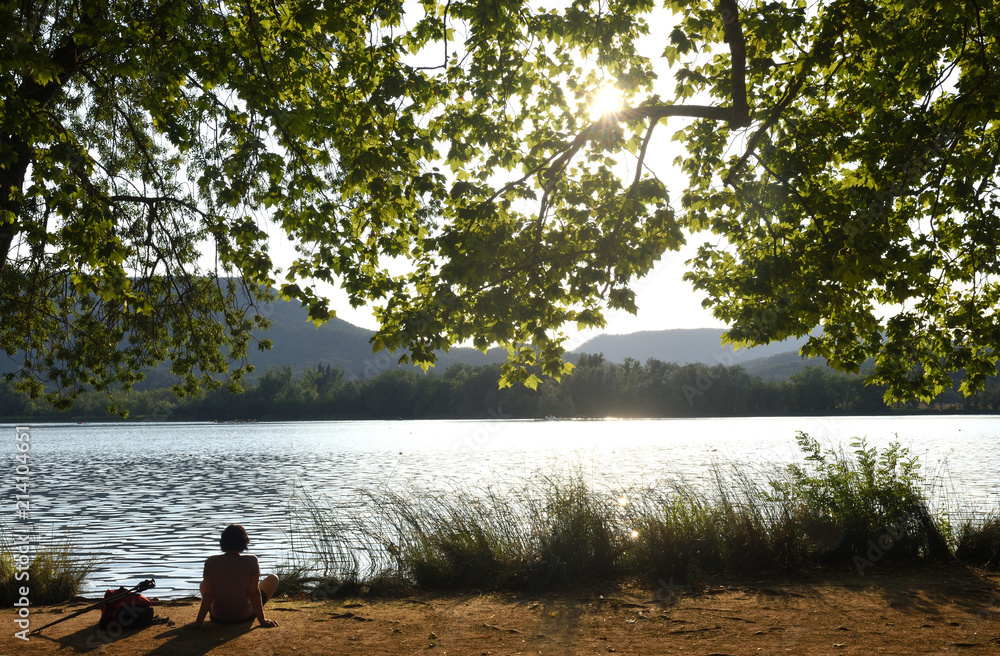 Woman looking at a lake when the sun sets