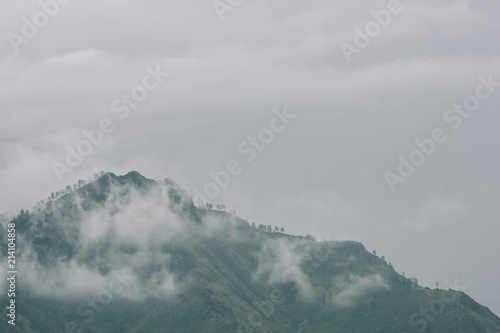 Thick fog in mountains with copy space on mist. Vintage foggy landscape of majestic nature in faded green tones in hipster style. Opaque haze among hills.