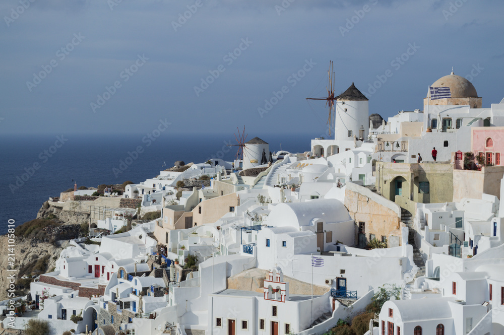 Naklejka premium Bielone domy i wiatrak na klifach z widokiem na morze w Oia, Santorini, Cyklady, Grecja