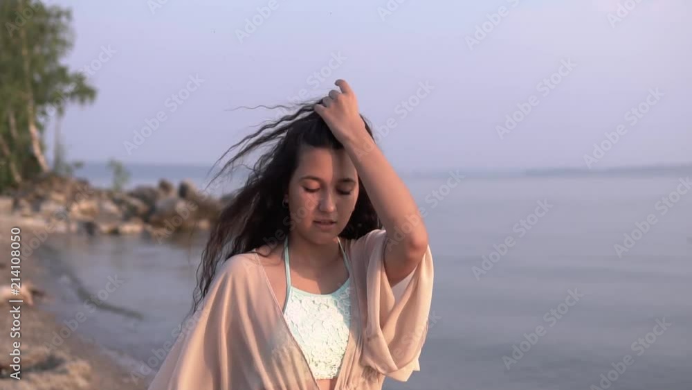 A beautiful girl in a beach tunic walks along the beach near the sea. slow motion. HD A beautiful girl in a beach tunic walks along the beach near the sea. slow motion. HD