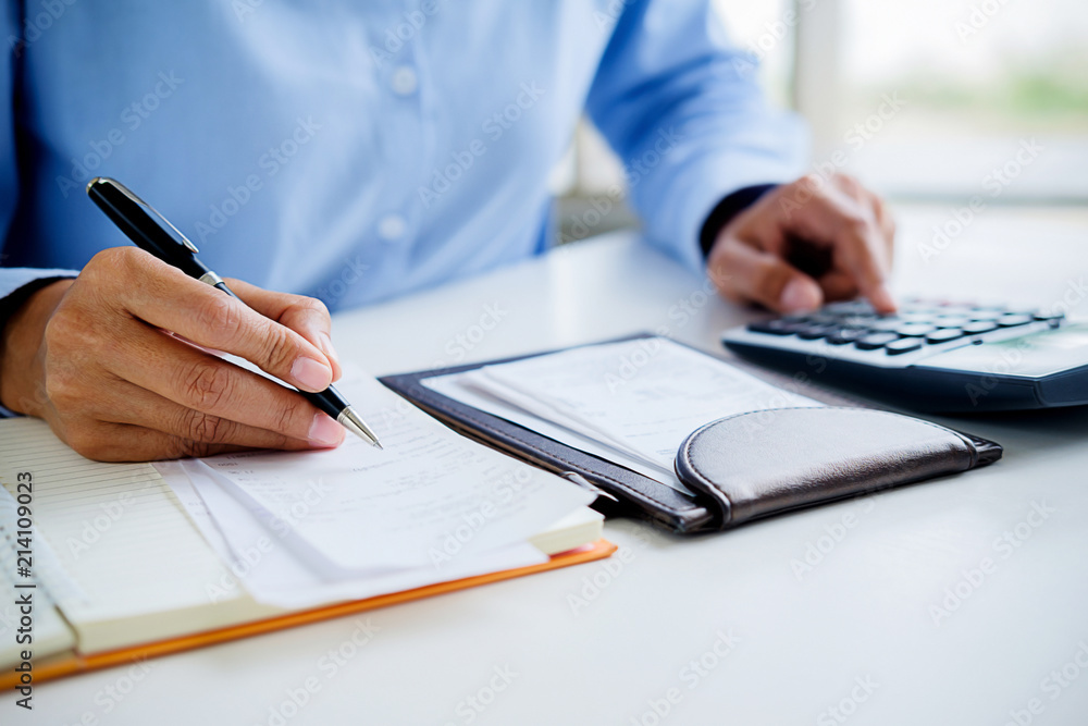 Woman with bills and calculator. Woman using calculator to calculate bills at the table in office. Calculation of costs. Woman with bills and calculator. Woman using calculator to calculate bills at the table in office. Calculation of costs.