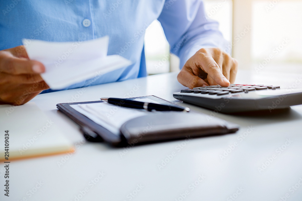 Woman with bills and calculator. Woman using calculator to calculate bills at the table in office. Calculation of costs. Woman with bills and calculator. Woman using calculator to calculate bills at the table in office. Calculation of costs.