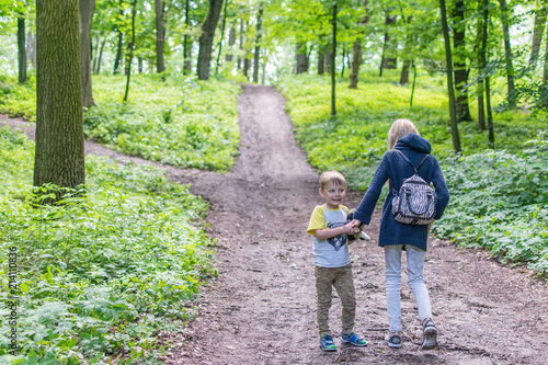 Two children walk along a forest path. The sister and the younger brother are going up the road in the forest.