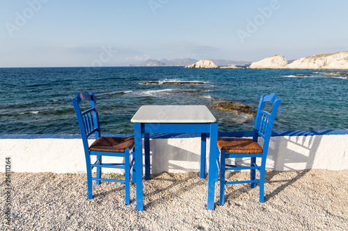 Table and chairs standing on the coast of Aegean sea in Greek island of Milos
