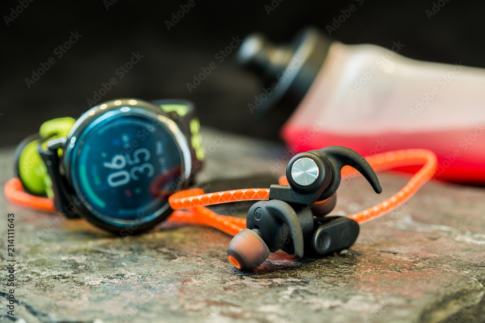 Obraz premium Headphones and sport equipment on dark background