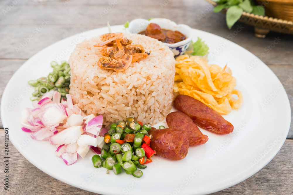 "Kao Cluk Ka Pi or Mixed Cooked Rice with Shrimp Paste on the wooden round dish. Thai Traditional food. - obrazy, fototapety, plakaty 