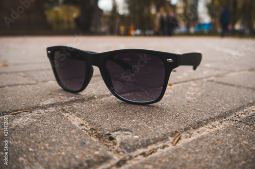 Sunglasses lie on the pavement on a sunny summer day