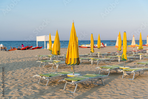 Yellow umbrellas and chaise lounges on the beach of Rimini in Italy