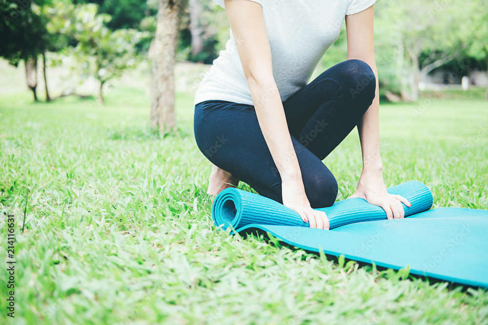 Fototapeta premium Yoga concept. Young woman meditates while practicing yoga in park. Calmness and relax, female happiness. blurred garden on the background